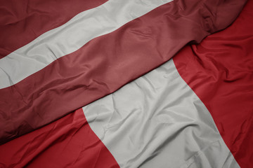 waving colorful flag of peru and national flag of latvia.