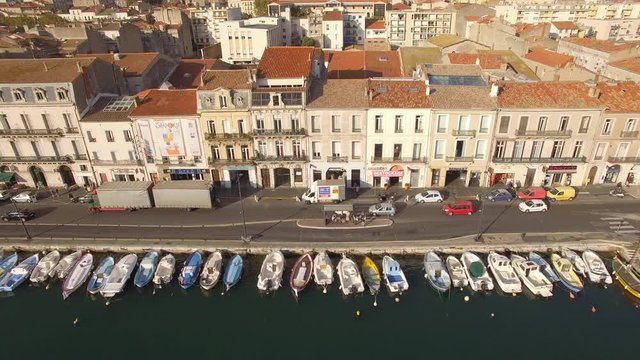 Sunrise drone shot on S&egrave;te. Nice traveling with cars driving along the channel with little fishing barque.Nice city colors in backround. The Venice of Languedoc.