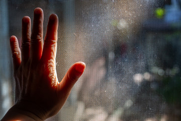 Woman's left hand touching dust Dirty mosquito wire screen window, Light & Shadow shot, Silhouette,...