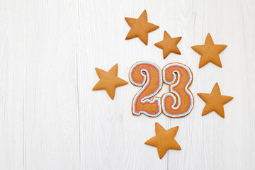 Gingerbreads in the form of stars and number "23" on Defender of the Fatherland Day on wooden background, copy space