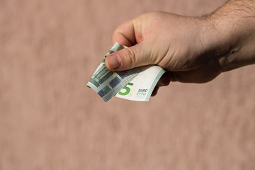 Man hands giving money like a bribe or tips. Holding EURO banknotes on a blurred background, EU...