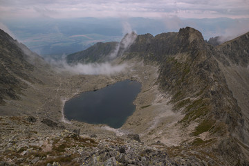 The hiking trail leads to the mountain lake in a beautiful valley with fog. Horizon and landscape...