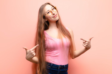 yound blonde woman looking proud, arrogant, happy, surprised and satisfied, pointing to self,...