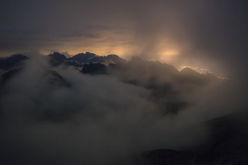 The valley is flooded in mist in a mountain environment. Over the fogs, only the high peaks of the...