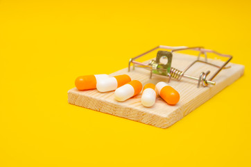 Mousetrap with pills on a yellow background. The concept of health, business