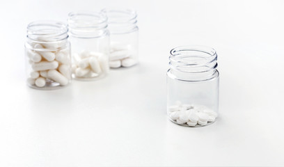 Four packages with various white pills and capcules on a white background. Health concept. Copy space.