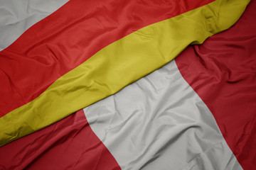 waving colorful flag of peru and national flag of south ossetia.