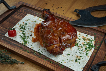 A classic dish of German and Czech cuisine is pork shank in beer and honey sauce on a wooden board. Beer snack. Tasty food close up. Roasted pork knuckle eisbein