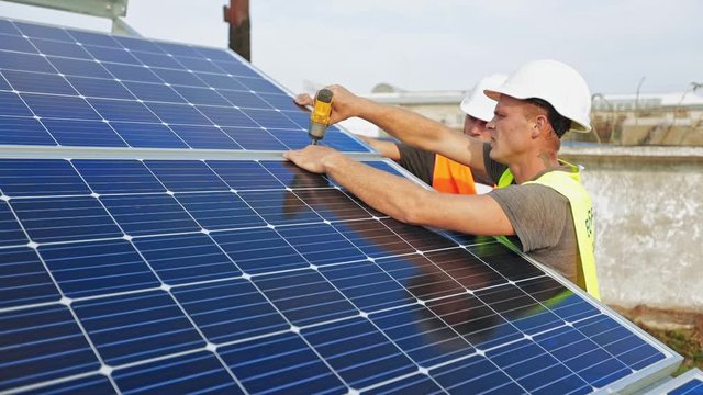 Technician installing solar cell. Technicians mounting photovoltaic solar panels