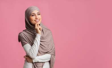 Beautiful muslim girl overthinking about something, looking away over pink background