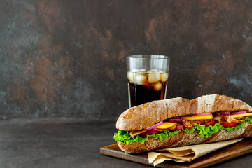A sandwich of dark bread with salad, bacon, tomatoes, cheese and onions. Breakfast. Fast food.