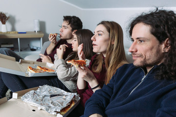 Two couples eating pizza and drinking beer. Movie night at home with friends