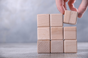 Hand arranging wood block stacking as step stair on wooden table. Business concept for growth...