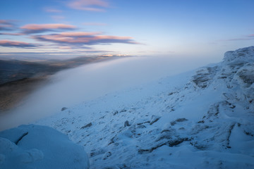 Low clouds and fog partly obscures the mountain ridge in winter
