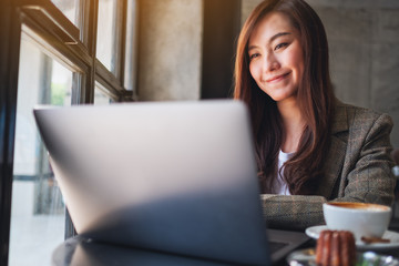 Closeup image of a woman working and typing on laptop computer in cafe