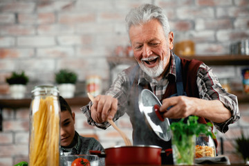Grandpa and grandson in kitchen. Grandfather and his grandchild having fun while cooking.