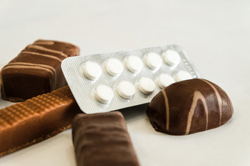 Chocolate candies and pills. Medicaments and sweets. Limited depth of field.