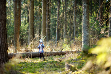 Cute little girl having fun during forest hike on beautiful spring day. Child exploring nature.