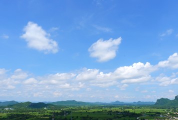 Fototapeta na wymiar Green rice field with mountains under blue sky. The fields are grassy green.It's rainy season.Sky in the rainy season