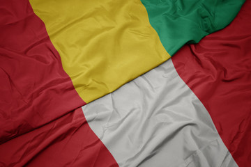 waving colorful flag of peru and national flag of guinea.