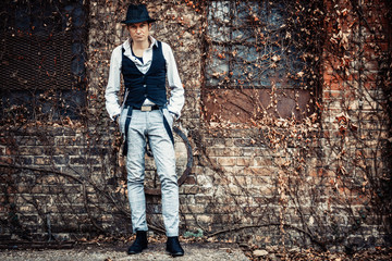 Full length of retro-styled man with a hat against brick wall.