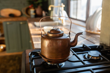 Metal copper teapot on a gas stove in the background of the kitchen. beautiful, copper, new tea, close-up