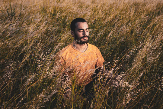  A young attractive man meditates yoga position on a natural bush park.