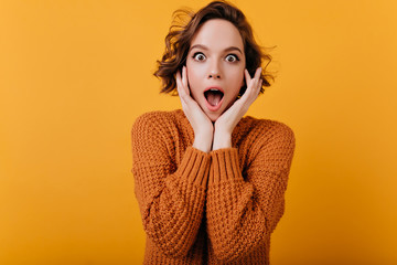 Fascinating white female model with trendy haircut expressing amazement and touching her face....