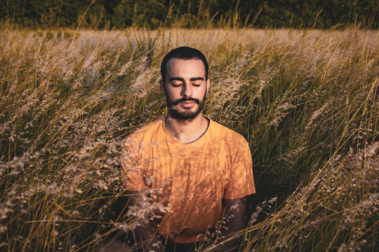  A young attractive man meditates yoga position on a natural bush park.