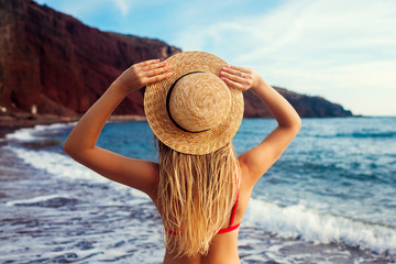 Sexy woman in bikini relaxing on Red beach in Santorini, Greece. Girl enjoying sea and mountain landscape
