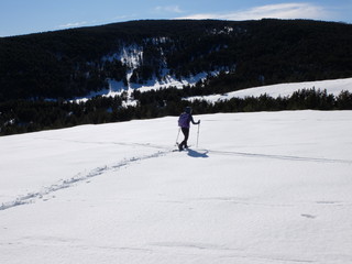 Fototapeta na wymiar Jeune femme randonneuse en raquette dans la neige en montagne sous le soleil des Pyrénées Orientales de Cerdagne