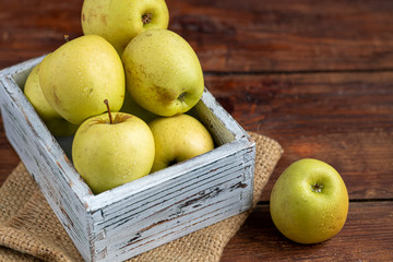 Golden apples are collected in a wooden, light, natural, environmentally friendly box. Harvesting. Delicacy for guests, vegetarian food, healthy food.