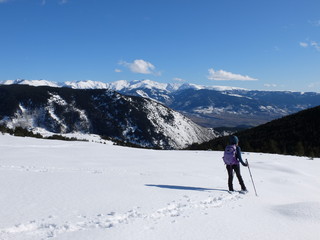 Jeune femme randonneuse en raquette dans la neige en montagne sous le soleil des Pyrénées Orientales de Cerdagne