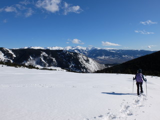 Jeune femme randonneuse en raquette dans la neige en montagne sous le soleil des Pyrénées Orientales de Cerdagne