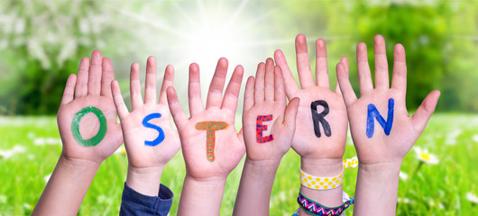 Children Hands Building Colorful German Word Ostern Means Easter. Green Grass Meadow As Background