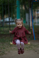 Happy caucasian child of two years old sitting on chain swing and swinging