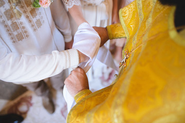 priest tying knot around hands of newlyweds