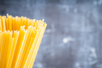 Raw dry spaghetti on the rustic wooden background. Selective focus.