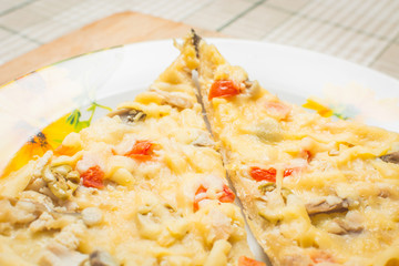 Cheese pizza with mushrooms, olives and tomatoes in plate on wooden board.