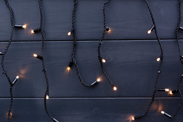 Garland lights on dark wooden wall. Background for design.