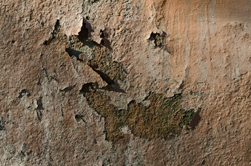 Old rusty surface. The paint is climbing off the wall. Old cracked paint. The wall is rusting.