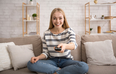Young attractive woman watching TV at home