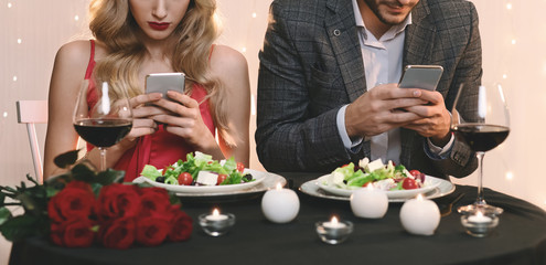 Man And Woman Stuck In Their Smartphones On Date In Restaurant