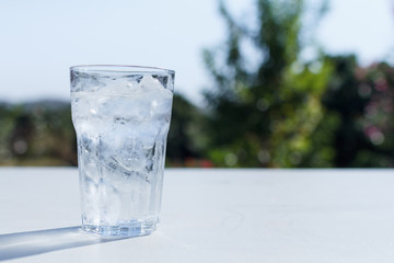 a glass of water with ice on the table.