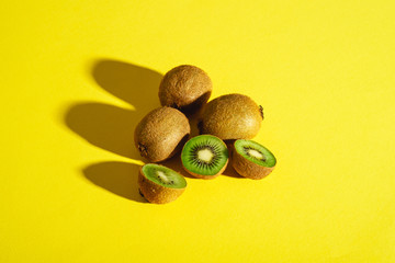 Kiwi fruits half sliced on vibrant plain yellow background, copy space, angle view