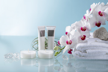 Spa  or wellness decoration with white  orchid, soft towel, two candle on light blue background. With copy space