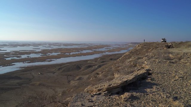 man gets out of the car to the shore of the drying Aral Sea on a sunny day 