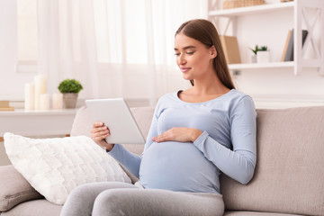 Obraz na płótnie Canvas Content Pregnant Woman Using Digital Tablet Reading At Home