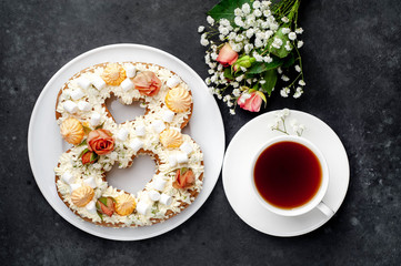tea and cake in the form of 8 is decorated with flowers, cream cheese, marshmallows, Bizet on a...