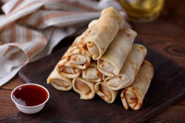 Russian pancakes with filling, lying on a wooden board with a slide